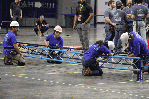 TK体育 engineering students work on their steel bridge, which earned first place at the ASCE 2023 symposium in March.